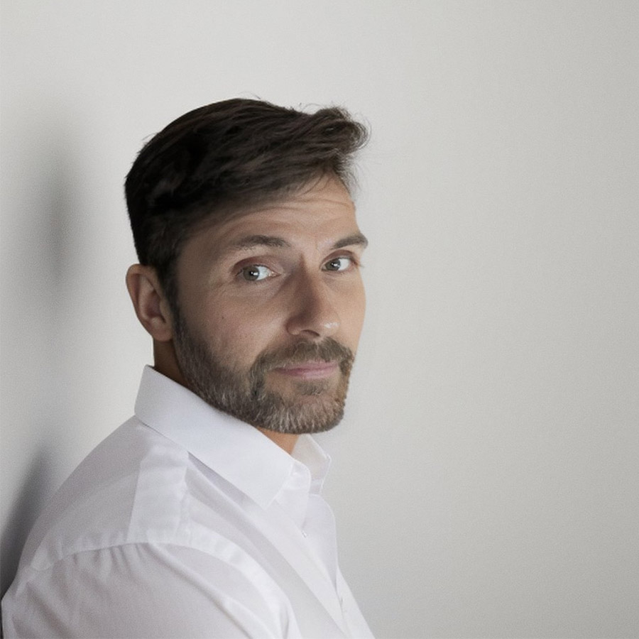 a man with a white shirt leaning against a white wall