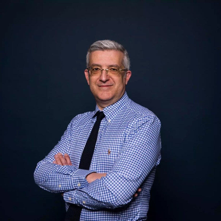 a man with a blue shirt standing in front of a dark background